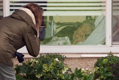 عکس/صحبت تلفنی دختر با مادر ۸۱ ساله کرونایی از پشت پنجره قرنطینه